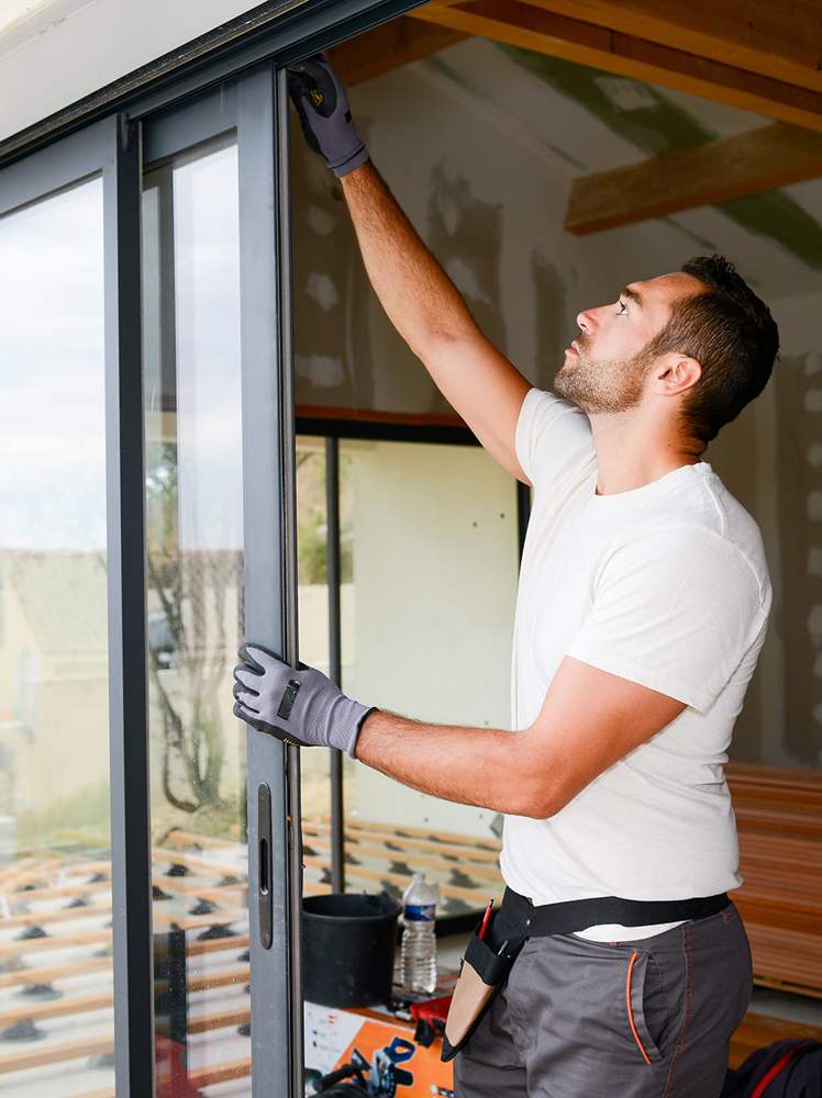 Poseur ajustant une baie coulissante aluminium